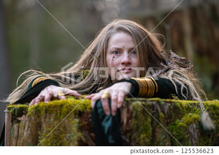 Woman leaning on tree trunk in forest. Shallow depth of feld 125536623