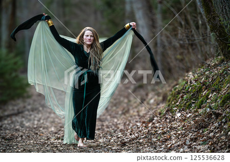 Woman dancing with veil in forest path. Shallow depth of feld 125536628