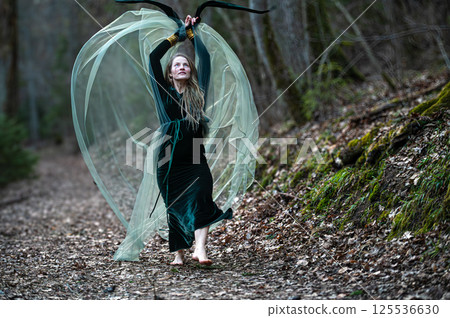 Woman dancing with veil in forest path. Shallow depth of feld Woman dancing with veil in forest path. Shallow depth of feld 125536630