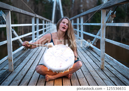 Woman playing drum on bridge. Shallow depth of feld 125536631