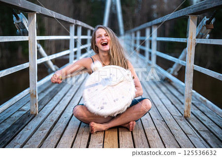 Woman playing a drum on a bridge. Shallow depth of feld 125536632
