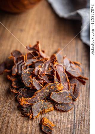 Beef jerky. Dried spiced meat on wooden table. 125537078