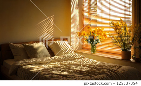 cozy bedroom scene where sunlight filters through blinds, casting warm patterns on neatly made bed adorned with soft pillows. Yellow flowers add touch of nature and comfort 125537354
