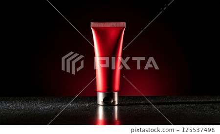 sleek, minimalist red cosmetic tube is dramatically illuminated against dark background, creating luxurious and elegant atmosphere. spotlight enhances its glossy finish 125537498