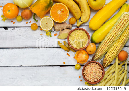 Autumn-themed arrangement of yellow and orange fruits and vegetables on a bright white wooden surface perfect for seasonal food promotions harvest celebrations and healthy eating concepts Autumn-themed arrangement of yellow and orange fruits and vegetables on a bright white wooden surface perfect for seasonal food promotions harvest celebrations and healthy eating concepts 125537649