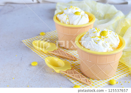 Three portions of vanilla ice cream with colorful candy decorations served in waffle cups with spring flowers on a bright background perfect for dessert menus summer promotions and sweet food concepts Three portions of vanilla ice cream with colorful candy decorations served in waffle cups with spring flowers on a bright background perfect for dessert menus summer promotions and sweet food concepts 125537657