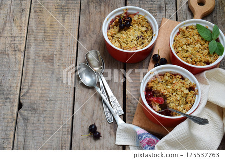Fruits casserole or crumble with apples and berries in brown cup ramekin. Copy space. Photographing with natural light. 125537763
