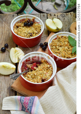 Fruits casserole or crumble with apples and berries in brown cup ramekin. Copy space. Photographing with natural light. 125537764