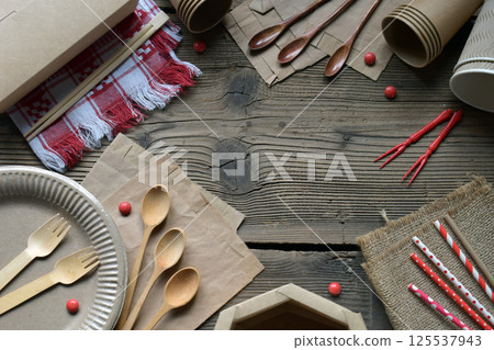 Sustainable Wooden and Paper Utensils for Green Living. Biodegradable Disposable Plates, Cups, Chopsticks, and Napkins Arranged on a Rustic Wooden Table for Eco-Conscious Dining Solutions 125537943