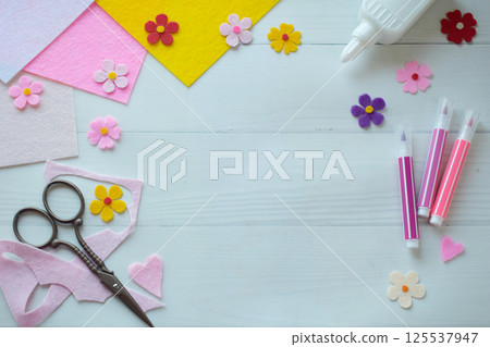 Flat lay composition of DIY greeting card crafting materials, including colorful felt flowers, scissors, glue, arranged on a white wooden background, showcasing the process of creating a personalized Flat lay composition of DIY greeting card crafting materials, including colorful felt flowers, scissors, glue, arranged on a white wooden background, showcasing the process of creating a personalized 125537947
