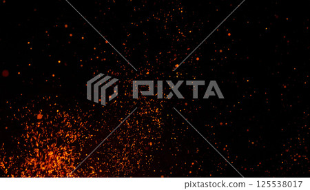 Magical golden orange embers float in dark night sky, creating mesmerizing display of tiny particles that resemble fireflies or sparkling stars 125538017