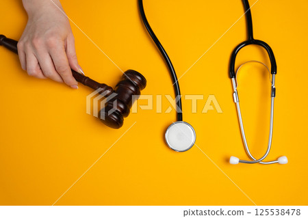 A woman holds a judge's gavel near a stethoscope. Medical law, healthcare crime and fraud concept. Medical rules 125538478