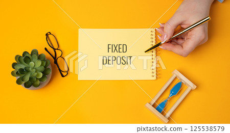 Fixed deposit concept. Financial product offered by banks and financial institutions where you deposit a lump sum of money for a fixed period of time at a fixed interest rate. A woman writes in notes 125538579