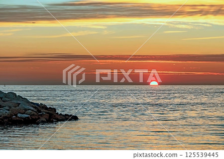Peaceful Sunset Over the Sea.A breathtaking sunset paints the sky with vibrant orange, pink and purple hues, casting a golden glow over the calm sea waters. Peaceful Sunset Over the Sea.A breathtaking sunset paints the sky with vibrant orange, pink and purple hues, casting a golden glow over the calm sea waters. 125539445