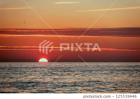Peaceful Sunset Over the Sea.A breathtaking sunset paints the sky with vibrant orange, pink and purple hues, casting a golden glow over the calm sea waters. Peaceful Sunset Over the Sea.A breathtaking sunset paints the sky with vibrant orange, pink and purple hues, casting a golden glow over the calm sea waters. 125539446