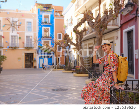 Woman strolls through colorful streets of Spanish coastal town 125539626
