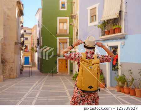 Woman strolls through colorful streets of Spanish coastal town 125539627