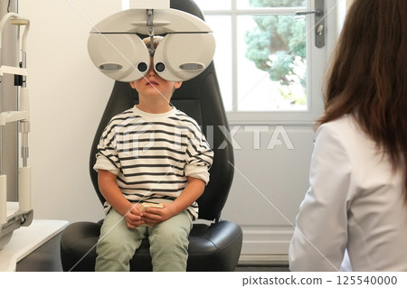 A little boy with ophthalmic equipment in clinic. 125540000