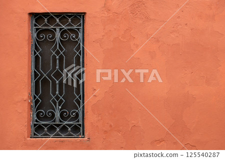 Decorative iron window on terracotta wall Decorative iron window on terracotta wall 125540287
