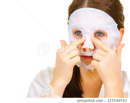 Woman applying sheet mask on face 125540543