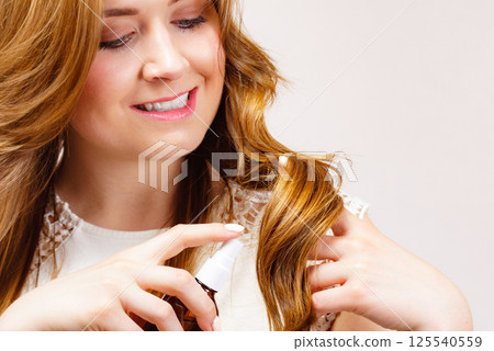 Woman applying hair cosmetic 125540559