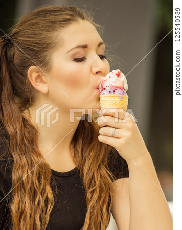 Young woman eating ice cream 125540589