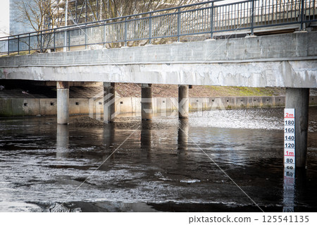 Concrete Bridge with Reflection Over Water and Depth Measurement Marker 125541135