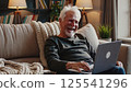 Elderly man enjoying digital device laptop entertainment home comfort retirement lifestyle modern technology senior learning relaxed atmosphere cozy living room evening leisure 125541296