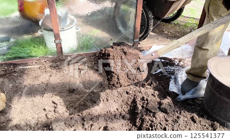 A farmer works on the land. Shoveling the earth in the greenhouse. Agricultural Labor Farmer Foot and Shovel in the Rural Field. man working on the ground 125541377