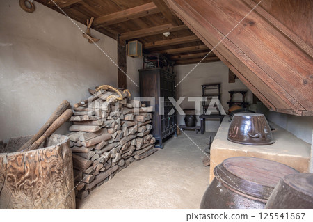 Traditional Korean storage room with stacked firewood wooden barrels shelves and earthenware jars under a rustic timber roof Traditional Korean storage room with stacked firewood wooden barrels shelves and earthenware jars under a rustic timber roof 125541867
