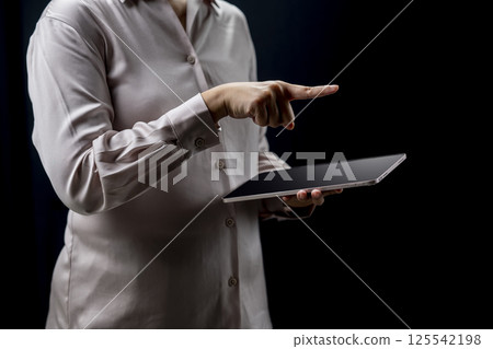 Businesswoman holding tablet while touching or pointing at something. Mockup and copy space. Business and technology concept 125542198