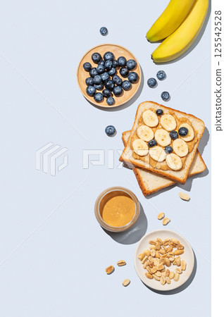 Peanut butter toast with banana, blueberry and nuts on a blue background. 125542528