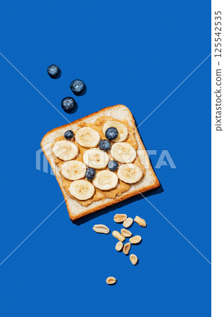 Peanut butter toast with banana, blueberry and nuts on a dark blue background. 125542535