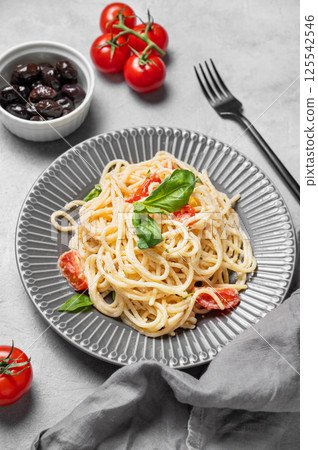 Delicious creamy spaghetti with cherry tomatoes, parmesan cheese and basil on a plate 125542546