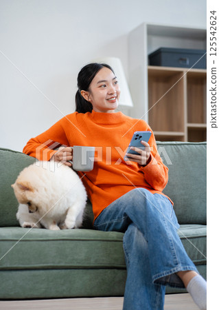 Lifestyle people, Happy woman sitting on sofa at home thinking and looking outside the window. Lifestyle people, Happy woman sitting on sofa at home thinking and looking outside the window. 125542624