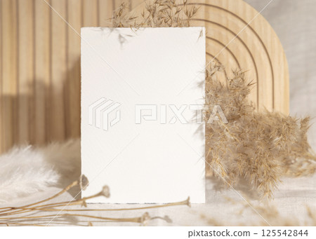 Blank card near dry pampas grass and beige wooden decor on linen closeup, minimal mockup Blank card near dry pampas grass and beige wooden decor on linen closeup, minimal mockup 125542844