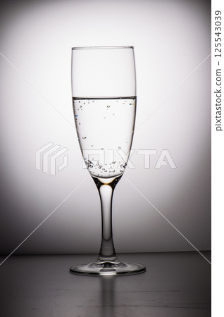A black-and-white photo depicting a long-stemmed glass. A glass of water. 125543039