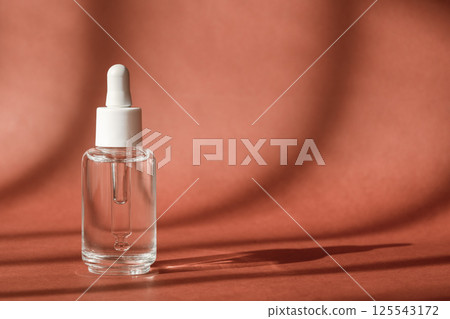 Serum cosmetic bottle, hyaluronic acid on brown background. Serum product cosmetic with peptide and collagen, modern brand glass cosmetics packaging. Cosmetic showcase Serum cosmetic bottle, hyaluronic acid on brown background. Serum product cosmetic with peptide and collagen, modern brand glass cosmetics packaging. Cosmetic showcase 125543172