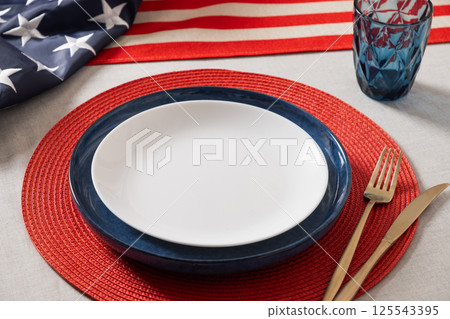 American table setting for USA Independence Day. Festive dinner decorated in USA national flag colors white, red and blue. Close up. Copy space. 125543395