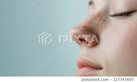 Close up profile of a young woman breathing, highlighting her nose and the freckles on her face, suitable for rhinoplasty and cosmetology themes 125543605