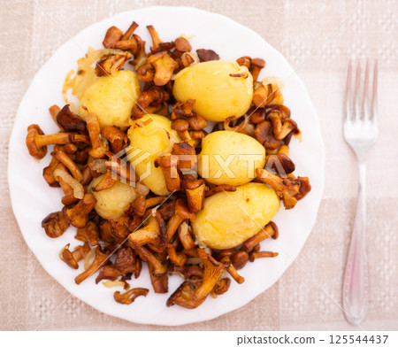Delicious fried chanterelles with new potatoes on a white plate top view Delicious fried chanterelles with new potatoes on a white plate top view 125544437