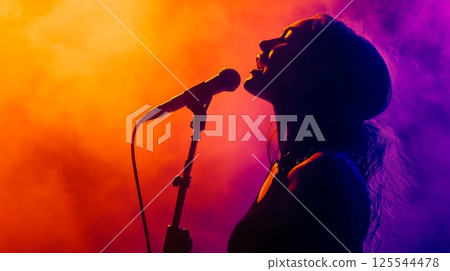 Silhouette of a female singer passionately singing into a microphone on a stage illuminated with vibrant orange and purple lights, creating a dramatic and artistic performance atmosphere 125544478
