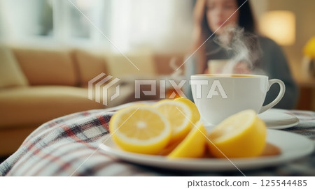 Steaming tea with lemon slices resting on a cozy blanket offers comfort and relief to a sick person lounging on a sofa, creating a soothing atmosphere during illness 125544485