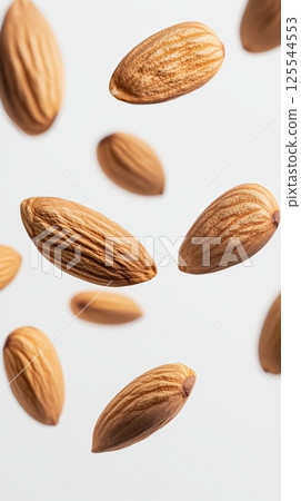 Levitating shelled almonds create an intriguing visual against a clean white background, highlighting the healthy and delicious qualities of these nutritious nuts 125544553