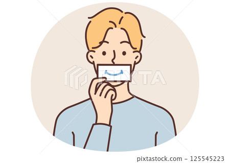 Man puts piece paper with image of smile to mouth, wanting to fake positive emotions during stress 125545223