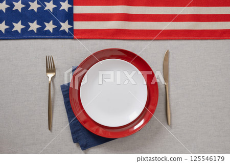Table setting for USA Independence Day. Festive dinner with empty white plate and decoration in USA national flag colors red and blue. View from above. Copy space. Close up. 125546179