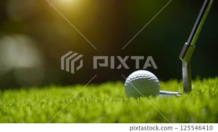 Golf clubs and golf ball on a green lawn in a beautiful golf course with morning sunshine. 125546410