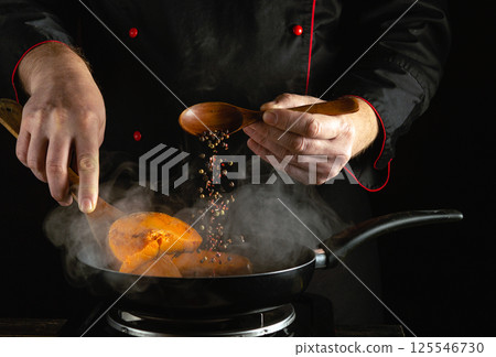 A skilled chef is seasoning vibrant seasonal vegetables in a frying pan. The scene showcases precise movements as spices are added, creating a flavorful dish in a professional kitchen A skilled chef is seasoning vibrant seasonal vegetables in a frying pan. The scene showcases precise movements as spices are added, creating a flavorful dish in a professional kitchen 125546730