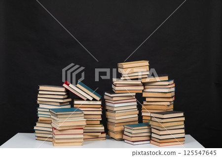 Stacks of old books for studying in the library on a black background of the university Stacks of old books for studying in the library on a black background of the university 125547645