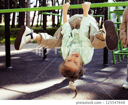 little cute girl with her mother and twin sister having fun on training playground outside 125547648